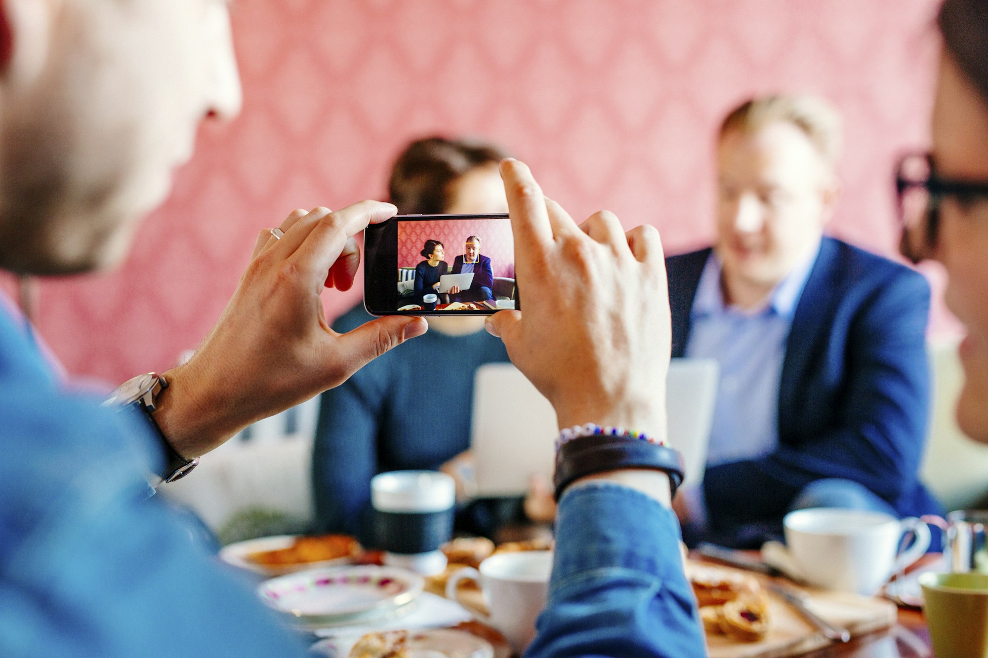 Cropped image of businessman photographing colleagues during meeting in office